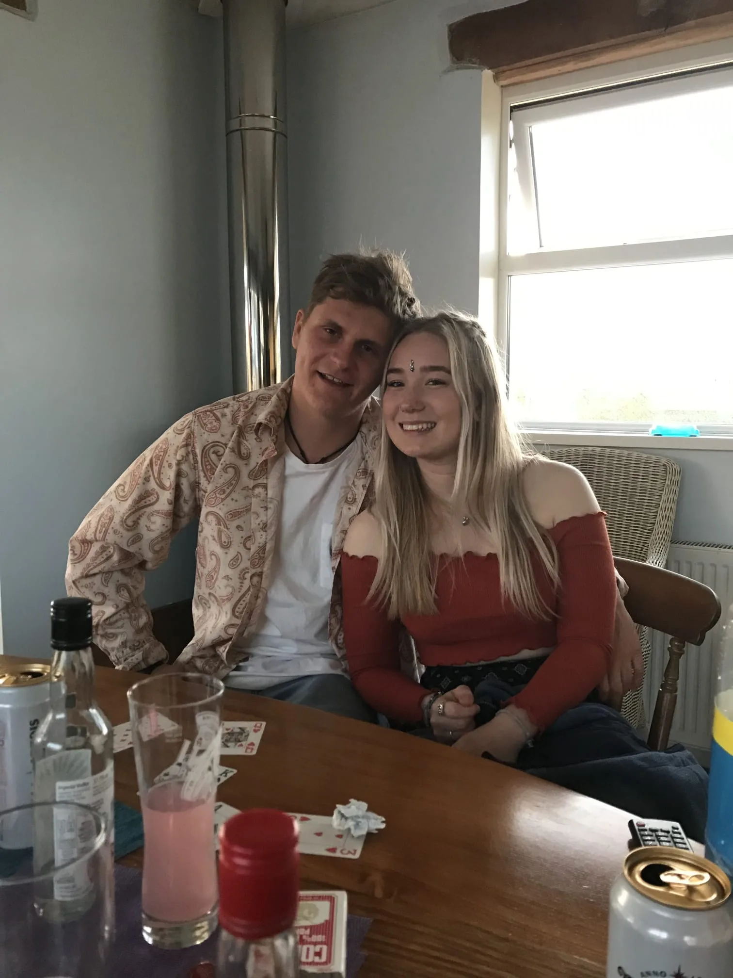 Tessa and Callum dressed up at a table with drinks, mid-party.