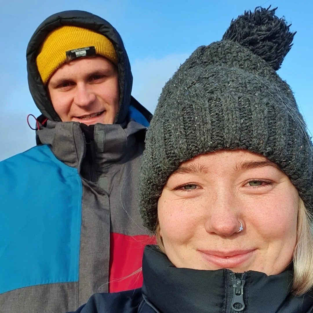 Tessa and Callum in bobble hats and winter coats on a bright, cold day.